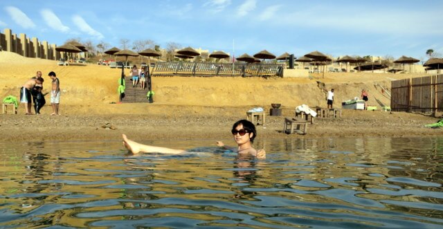 Floating in the Dead Sea. You can see the beach behind and men liberally rubbing mud over each other...